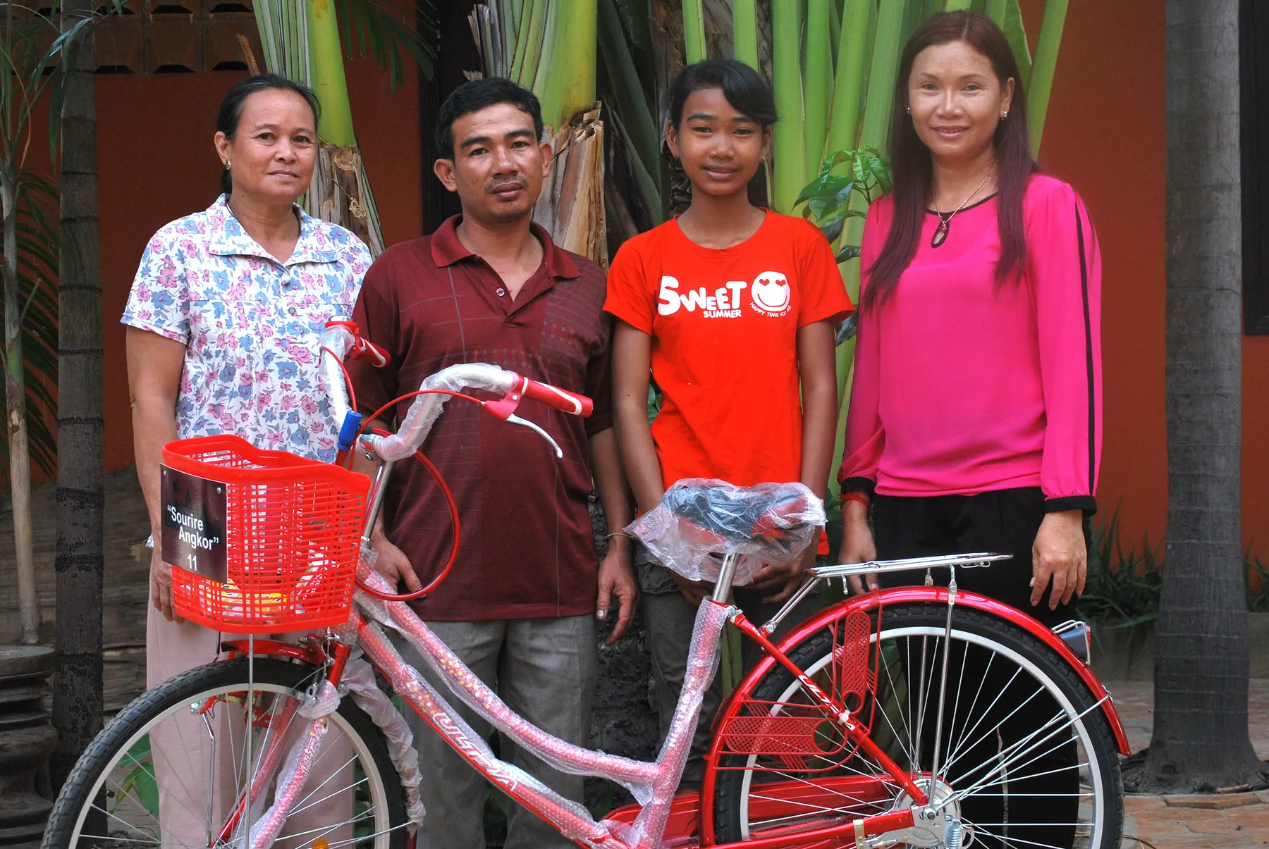 Une famille et la responsable de l'association lors de la remise d'un vélo